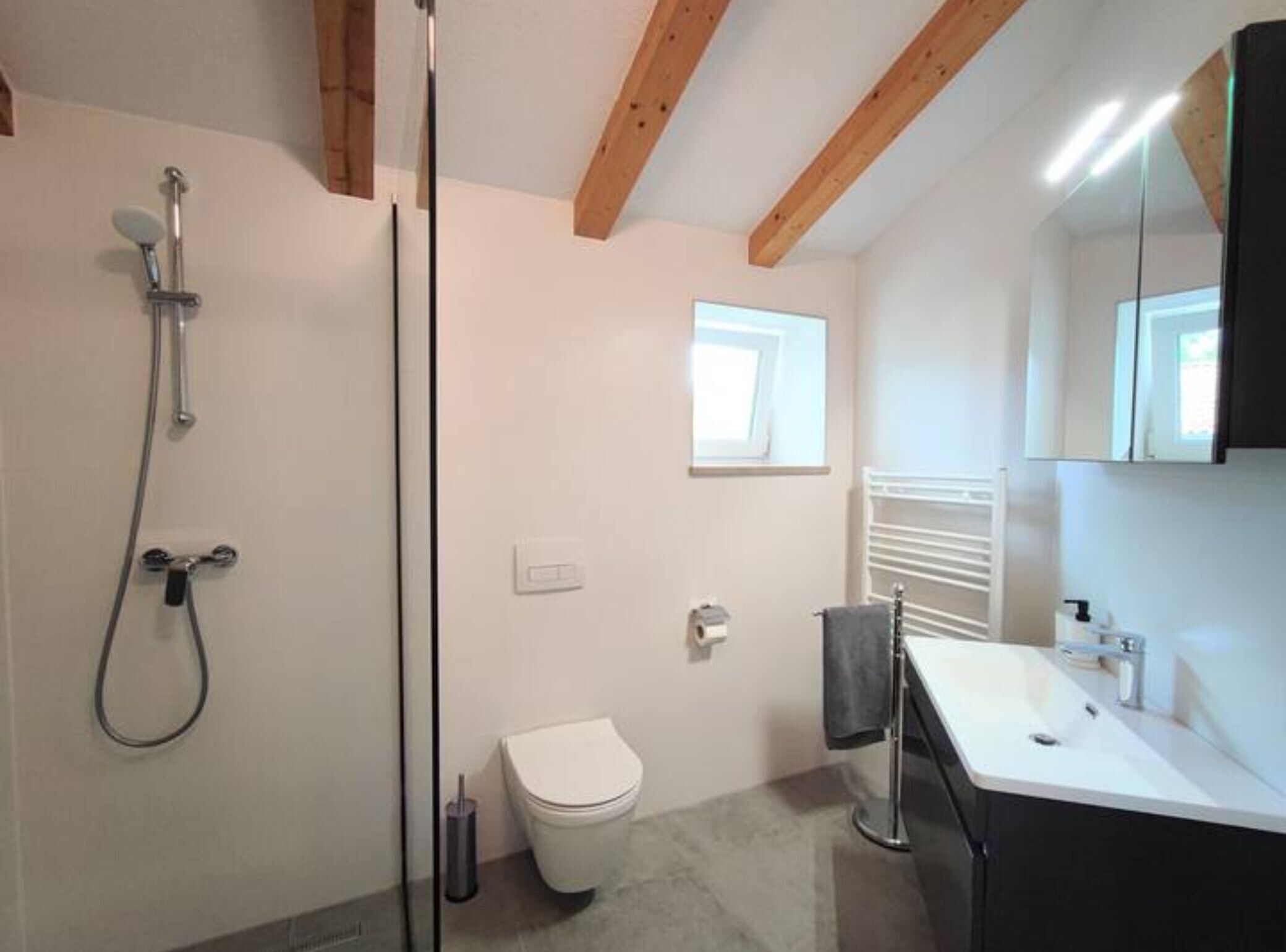 Un baño con ducha, inodoro, lavamanos y ventana.