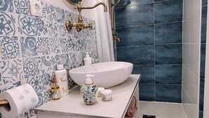 A bathroom with a white sink, patterned tiles, and a shower area.