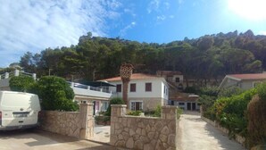 Une villa blanche avec une entrée en pierre, un fourgon garé et un chemin menant à la maison.