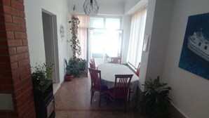 Un coin repas avec une table ronde et des chaises, des plantes en pot et une vue sur l’extérieur.