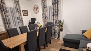A modern living room with a wooden dining table, grey sofas, and a grey couch. - Apartment and Room Mare Vrlika - Double Bedroom with Terrace and External Kitchenette (Sinj)