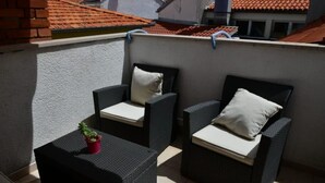 A balcony with two wicker chairs, a small table, and a potted plant.