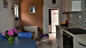 A compact kitchen with a dining area, a sofa, and a small table with flowers.