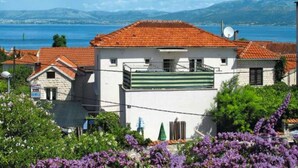 A coastal building with a red-tiled roof, white walls, and a balcony.