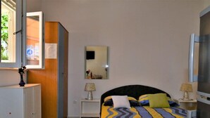 A bedroom with a bed, bedside tables, a wardrobe, a mirror, and a TV.