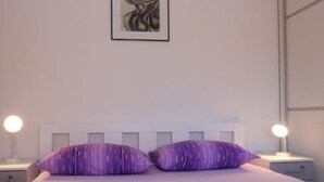 Une chambre à coucher avec un lit, deux tables de chevet et un tableau accroché au mur.