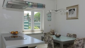 Une cuisine moderne dotée d’une cuisinière intégrée, d’une table à manger avec des chaises à motifs floraux et d’une fenêtre donnant sur un paysage verdoyant.