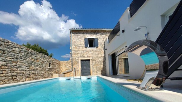 A swimming pool with a stone wall on one side and a modern building with a door and window on the other. - Villa Galant with Pool & Sauna Maružini (Kanfanar)