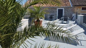 A rooftop terrace with a stone wall, a potted plant, and outdoor furniture. - Villa Galant with Pool & Sauna Maružini (Kanfanar)