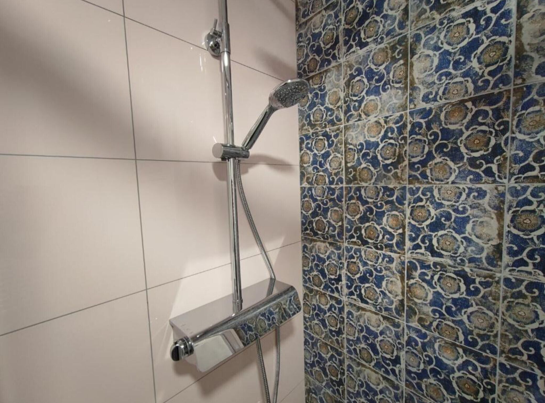 A shower with a handheld showerhead and a handheld bar.