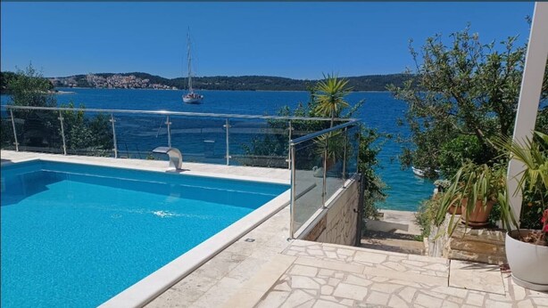 A swimming pool with a clear view of the sea and a sailboat in the distance. - Apartments Bilić Trogir - Two-bedroom Apartment With Sea View (A1) (Trogir)