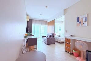 A modern living room with a dining area, a sofa, a small table, and a fan. - Veranda Residence 1Bed By Thita (Sattahip)