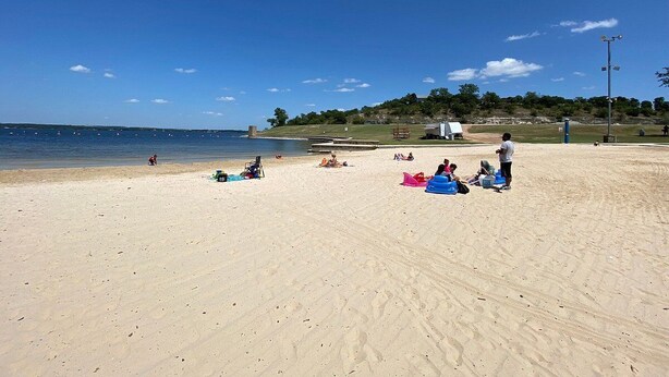 Zandstrand met mensen die ontspannen en enkele strandstoelen.