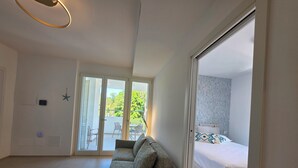A modern hotel room with a grey sofa, a bed with patterned pillows, a balcony with chairs, and a star decoration on the wall. - M4ree Seaside Suite And Relax (Bari)