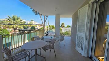 A balcony with a round table and chairs, a potted plant, and a view of the cityscape.
