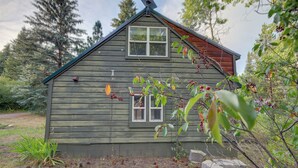 Une cabane rustique avec un toit à pignon, une petite véranda et une fenêtre.
