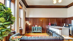 Een moderne keuken met een bar, houten lambrisering en een grote potplant.