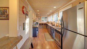 A modern kitchen with wooden floors, a stainless steel refrigerator, and a wooden ceiling.