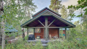 A cabin with a wooden exterior, a covered porch, and a small deck area.