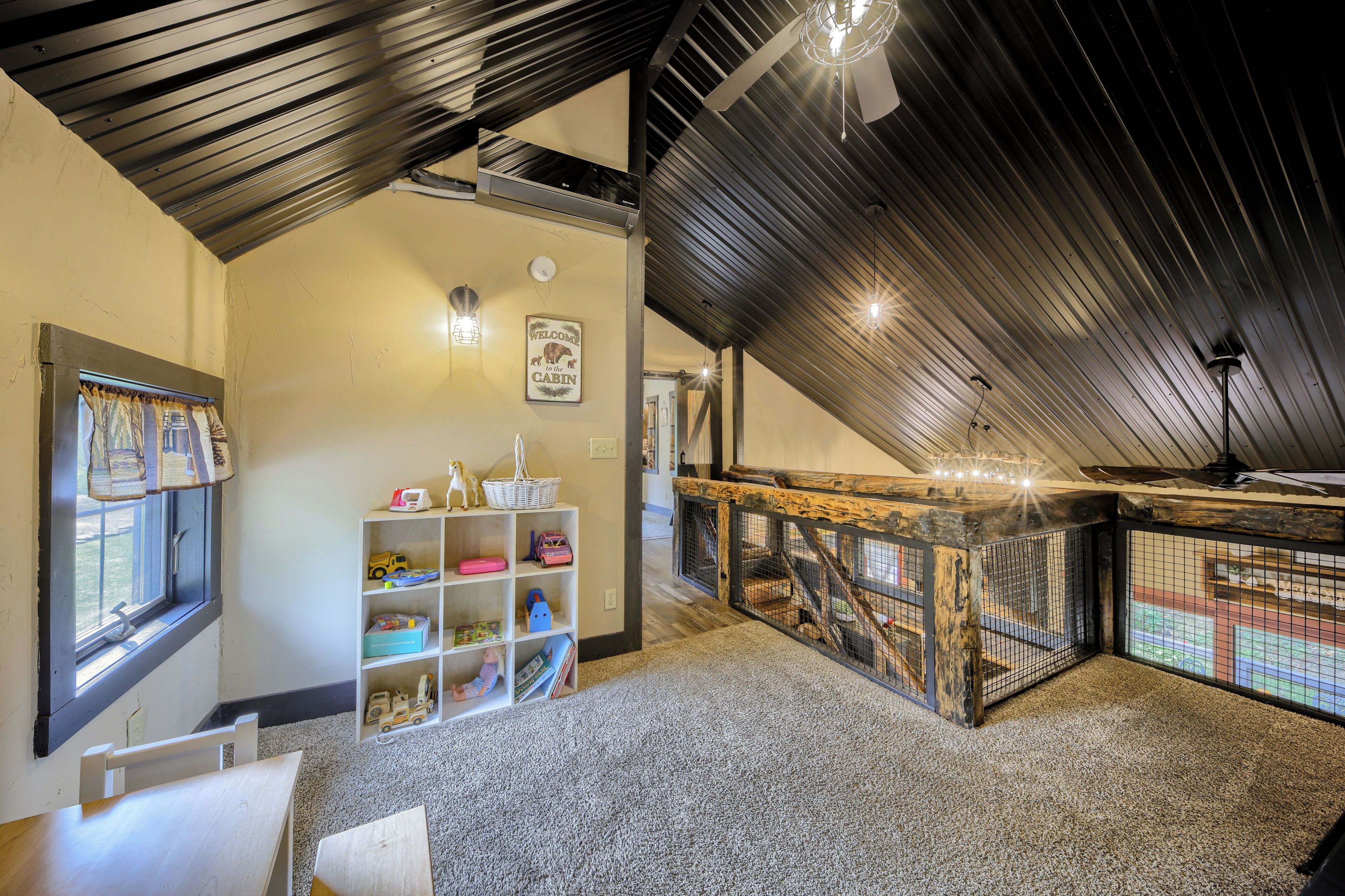 Une pièce mansardée chaleureuse, avec un plafond en pente, un espace de jeux en bois et une fenêtre avec des rideaux.