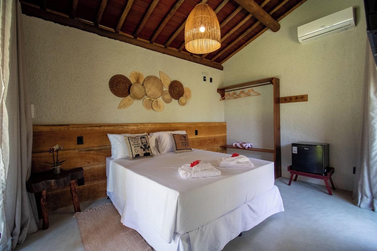 Ein Schlafzimmer mit einem großen Bett, einem Holzkopfteil, einer Hängeleuchte und einem kleinen Fernseher auf einem Schrank.