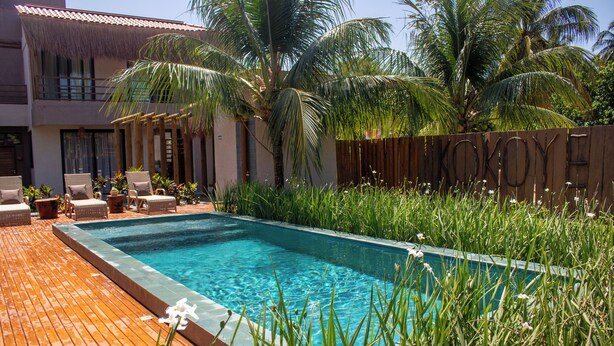 Una piscina con tumbonas y plantas tropicales.