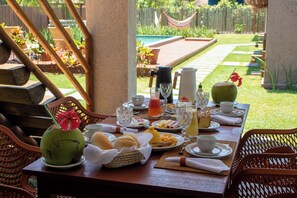 Una mesa de desayuno lista con diferentes platos, bebidas y una decoración central de frutas.