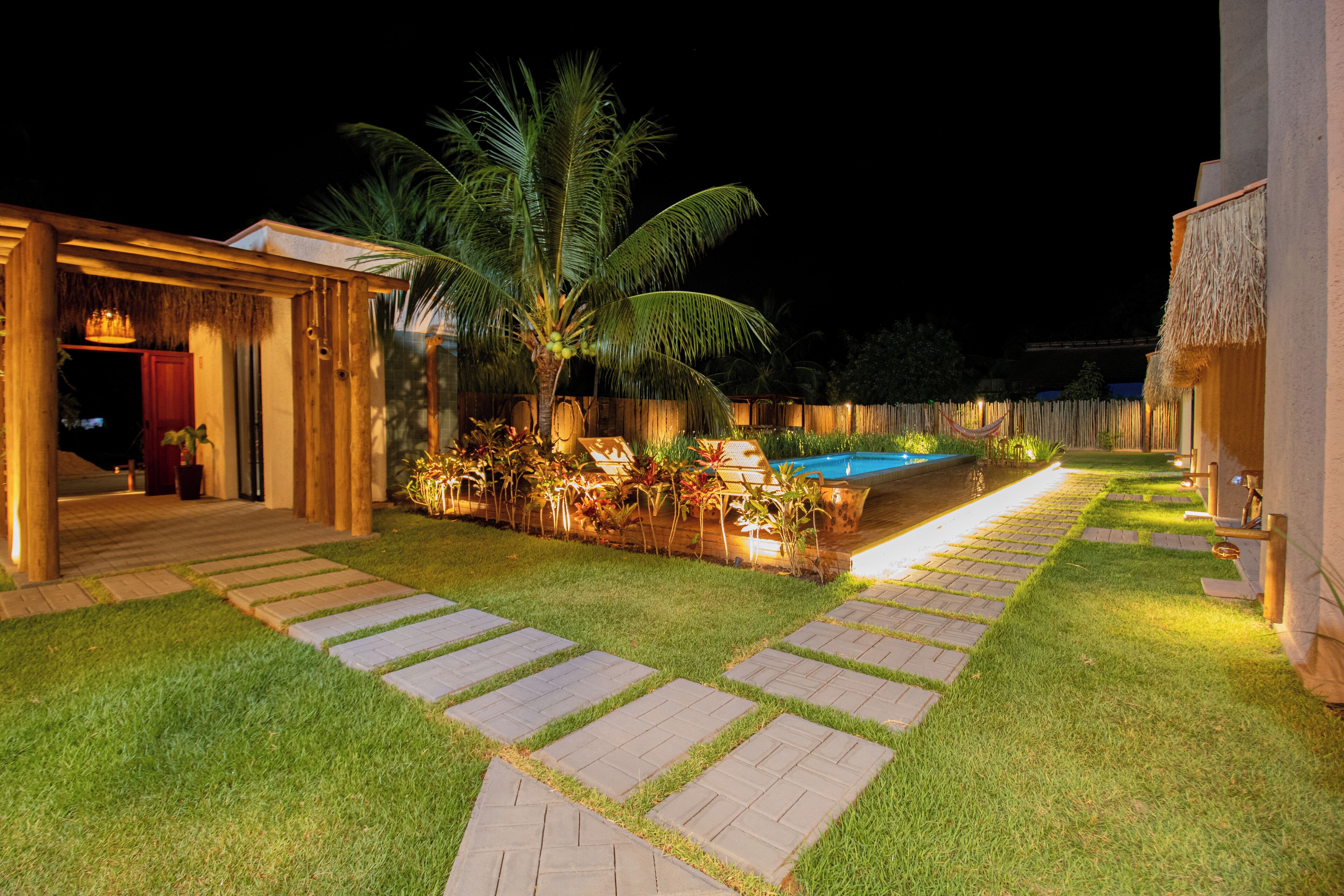 A well-lit outdoor area with a pool, palm trees, and a wooden deck.