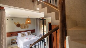 Un dormitorio con cama, cabecera de madera, lámpara colgante y vistas al exterior.