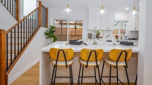 A modern kitchen with white cabinetry, a central island with bar stools, and pendant lighting.