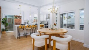 A modern kitchen with white cabinets, a central island with bar stools, and a chandelier.