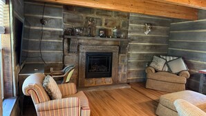 L’intérieur d’un chalet confortable, avec une cheminée en pierre, un plancher en bois et des meubles rustiques.