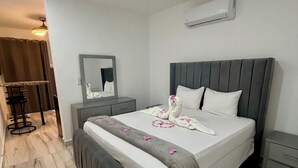 A neatly arranged hotel room with a large bed, a bedside table, a mirror, and a modern air conditioning unit on the wall. - Charming 1-bedroom studio facing the pool, in the heart of Sosua (Sosúa)
