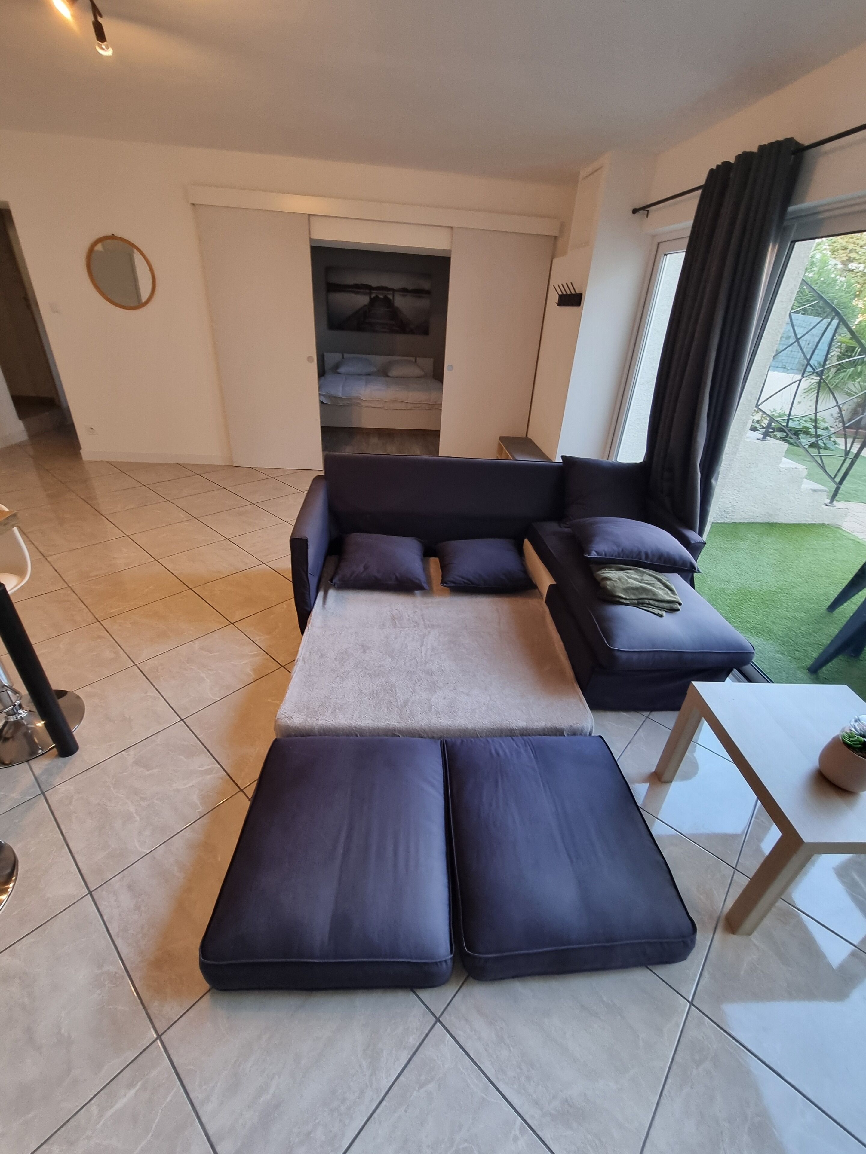 Uma sala de estar moderna com um sofá, uma mesinha e vista para um jardim.