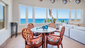 Ein Zimmer mit einem großen Fenster zum Meer, einem runden Tisch mit Stühlen und einer Couch mit Aussicht.