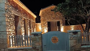 Un edificio de piedra con entrada porticada y ventanas iluminadas por la noche.