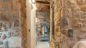 Un pasillo de paredes de piedra que conduce a un dormitorio con cama y mesita de noche.