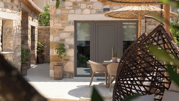 Edificio de piedra con un patio, que incluye una mesa, sillas y un sillón colgante.