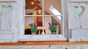 A rustic room with a white-painted window framed in distressed wood, two heart-shaped cutouts, and a view of a dining area with a table and chairs. - Vacation apartment Ackerblick on a beautiful vacation farm near the Baltic Sea (Schwartbuck)