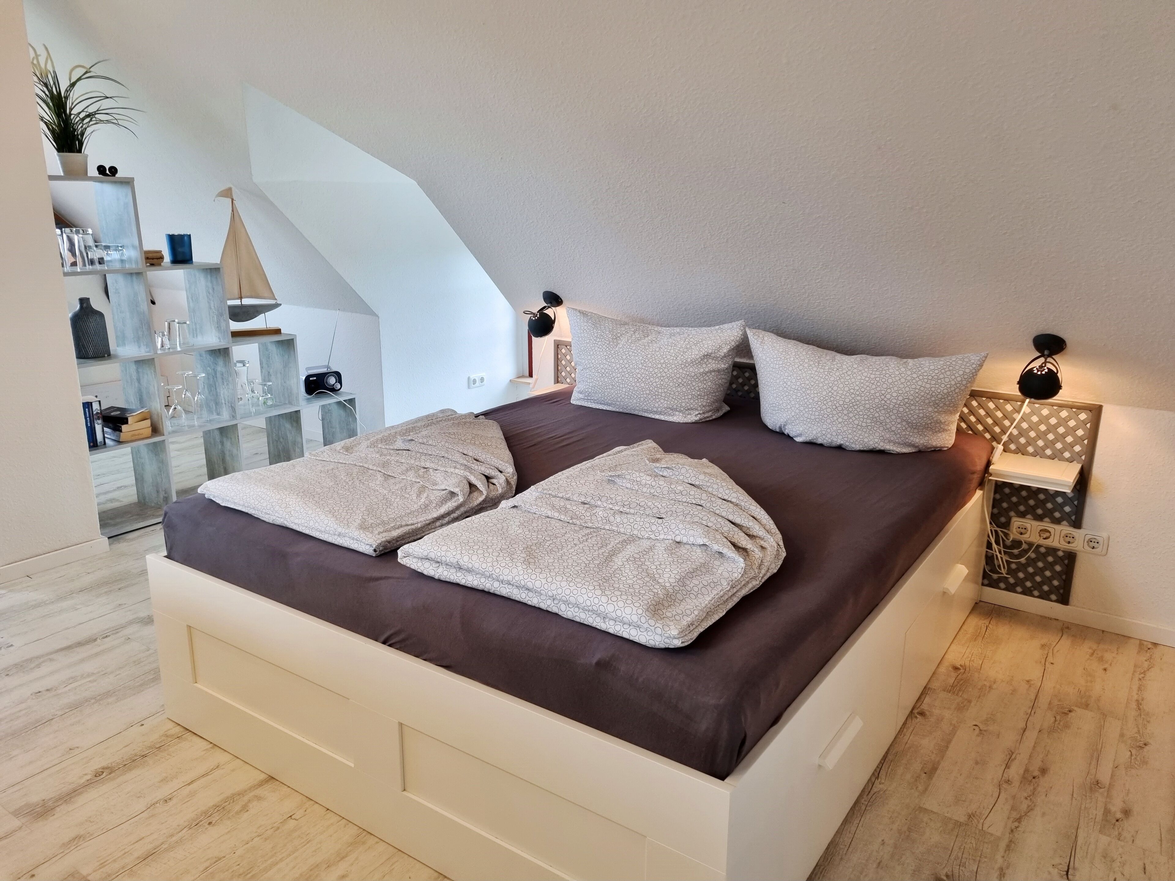 A modern bedroom with a large bed, bedside tables, a lamp, and a view of a staircase.