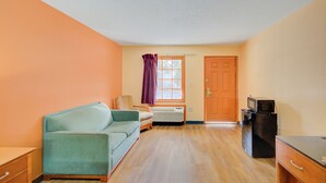 A compact living space with a sofa, a small table, a microwave, and a door. - Hotel O Deluxe Inn Kingstree Sc Hwy 52 (Kingstree)