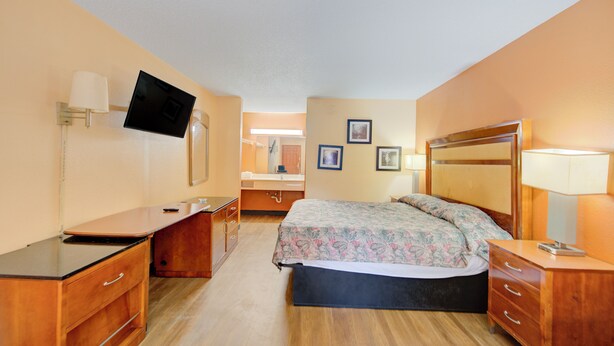 A hotel room with a bed, a desk, a chair, a TV mounted on the wall, and a bathroom visible through an open door. - Hotel O Deluxe Inn Kingstree Sc Hwy 52 (Kingstree)