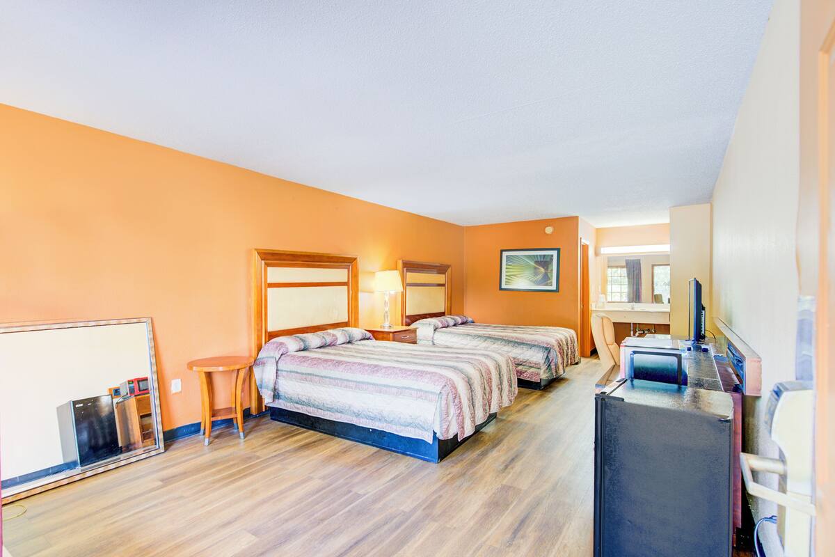 Une chambre d’hôtel avec deux lits, un bureau, une chaise et un téléviseur.