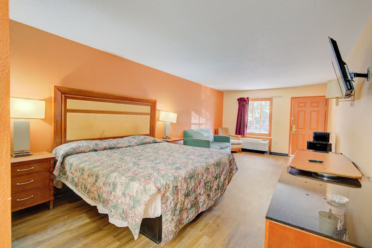 Une chambre à coucher avec un lit, un bureau, une chaise et un téléviseur.