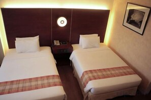 A hotel room with two beds, a nightstand, a lamp, and a framed picture on the wall. - Casablanca Suites Near Airport (Legaspi)