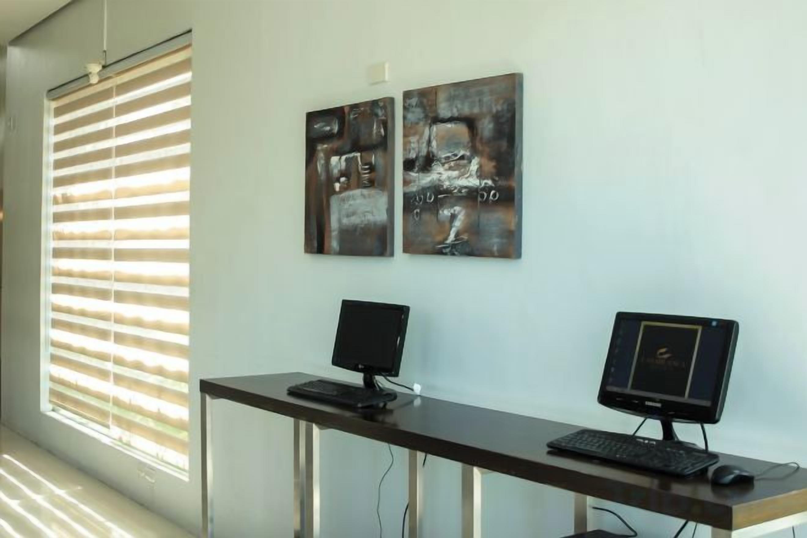 A room with a desk, two monitors, and artwork on the wall.