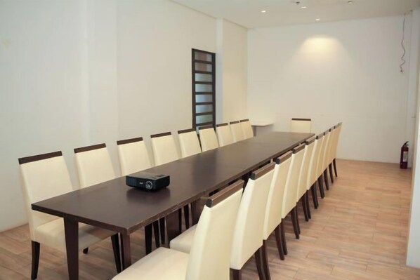 A conference room with a long table, chairs, a projector, and a fire extinguisher.