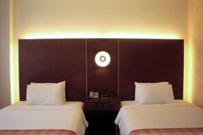 A hotel room with two beds, a nightstand, and a wall-mounted light fixture. - Casablanca Suites Near Airport (Legaspi)