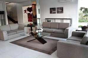 Una sala de estar con un conjunto de sofá, una mesa de centro y una escalera que conduce a otro nivel.