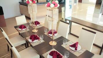 A dining table set with white plates, red napkins, and clear glasses, flanked by tall, decorated vases.